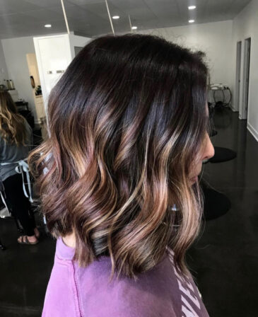 Shoulder-length dark brunette waves with warm caramel balayage
