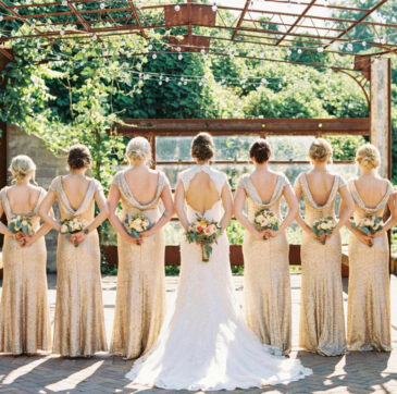 Bride and bridesmaids in champagne gowns, back view, showing their coordinated hairstyles
