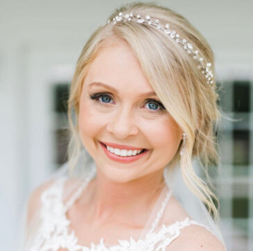Smiling blonde bride with soft curls, a jeweled headband and veil