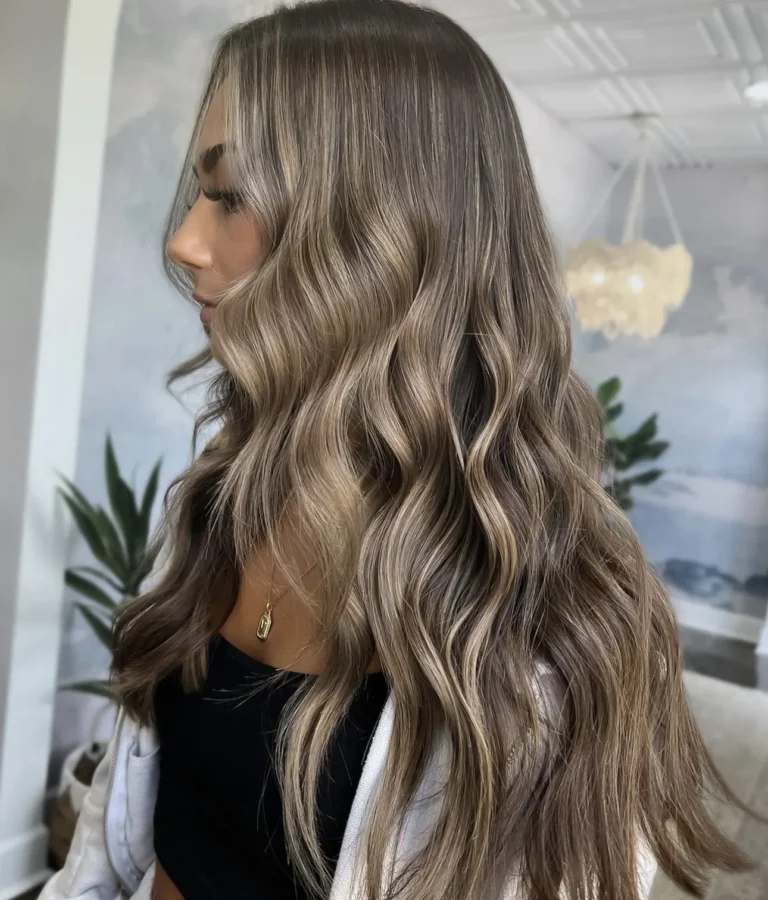 Long bronde balayage waves blending smoky brown roots into lighter ends, side profile