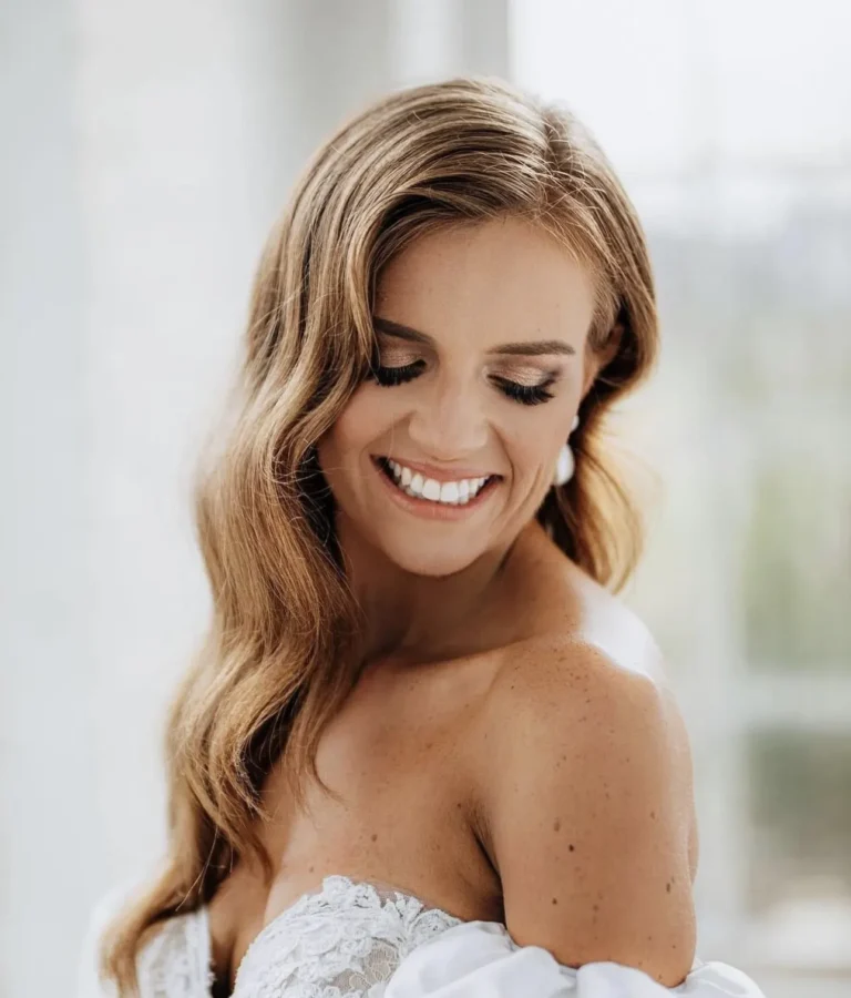 Smiling bride with glamorous side-swept Hollywood waves for her wedding day