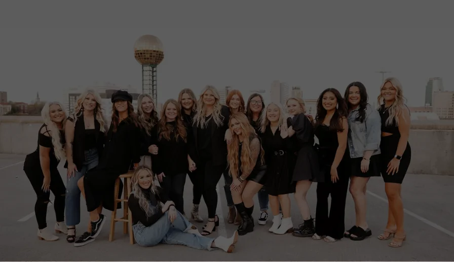 The Whitney Evans Beauty team on a rooftop with the Knoxville Sunsphere behind them
