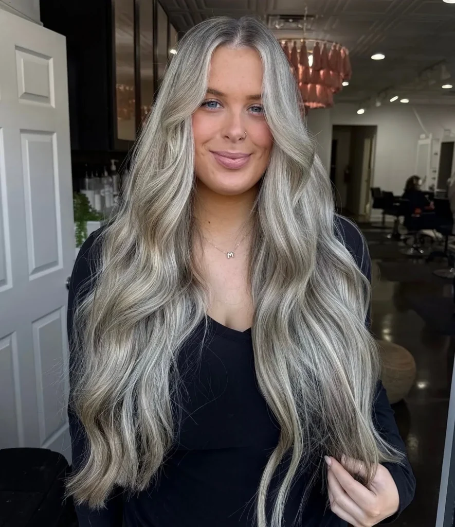 Long ash blonde balayage with bright dimensional highlights in loose waves at Whitney Evans Beauty