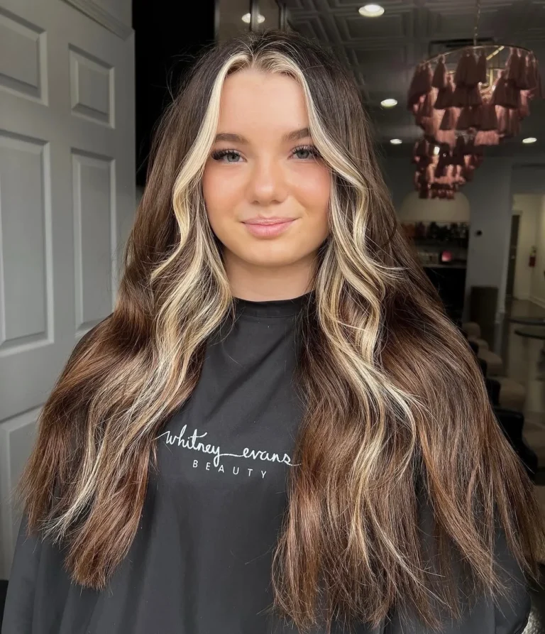Brunette waves with a bold platinum money piece framing the face